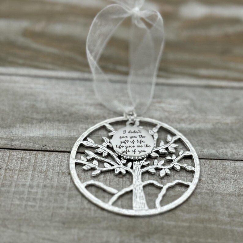 May include: Silver tree of life ornament with a round charm that reads "I didn't give you the gift of life, life gave me the gift of you".