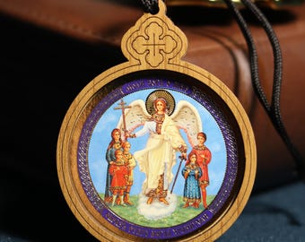 May include: Wooden pendant with a religious icon featuring an angel with a halo, surrounded by figures in colorful robes. The pendant has a round shape with a wooden frame and a black cord for wearing.