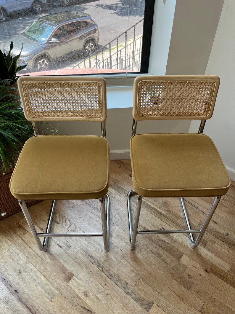 May include: Two mustard yellow velvet upholstered chairs with cane backs and chrome frames.