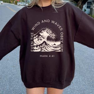 May include: Black sweatshirt with a white graphic of a wave and the text "Even the wind and waves obey him Mark 4:41"