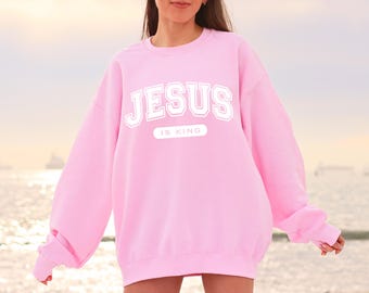 May include: Pink sweatshirt with the text "JESUS IS KING" in white.