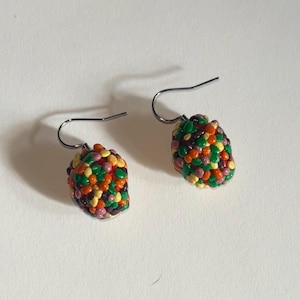 May include: A pair of dangle earrings with a small, round, multi-colored bead. The bead is made of small, round, colorful beads in shades of green, orange, yellow, brown, and pink.
