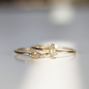 May include: Two gold rings with marquise-shaped diamonds. The diamonds are a light brown color.