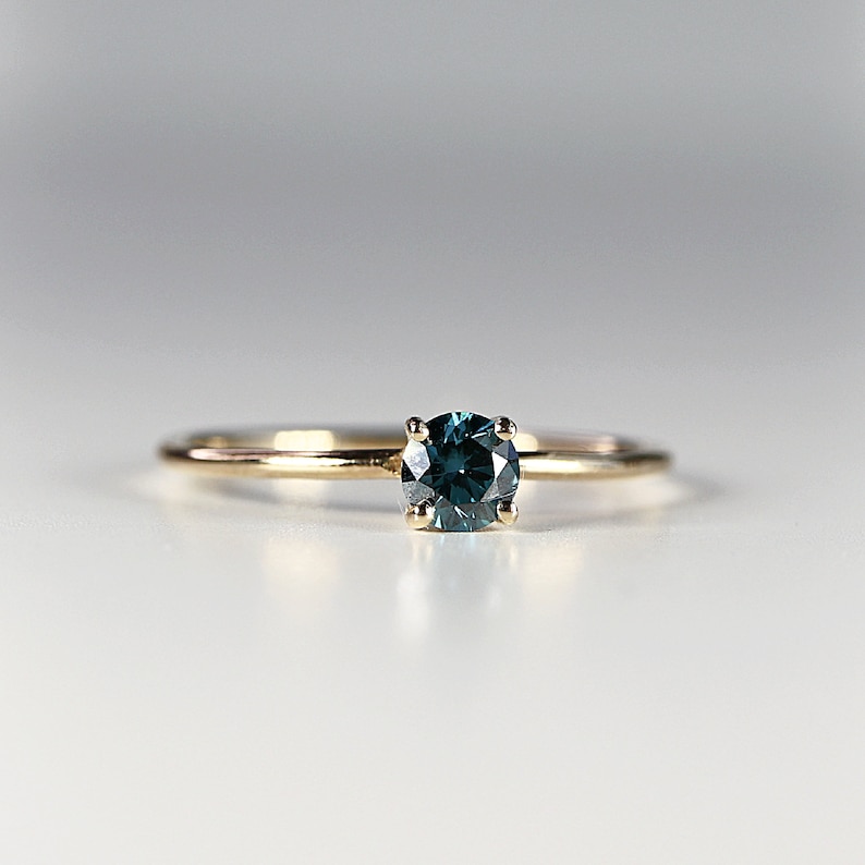 Puede incluir: Un anillo de banda de oro con una piedra preciosa azul turquesa.