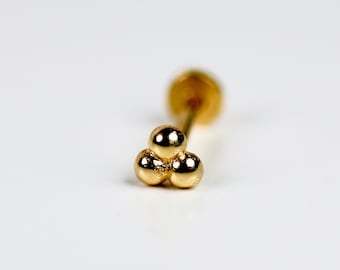 May include: Gold nose stud with three small round balls.