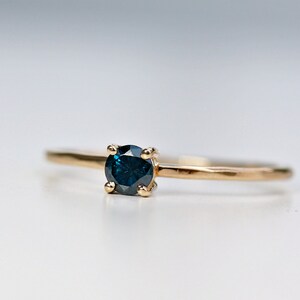 Puede incluir: Un anillo de oro con una piedra preciosa azul oscuro engastada en un engaste de cuatro garras.