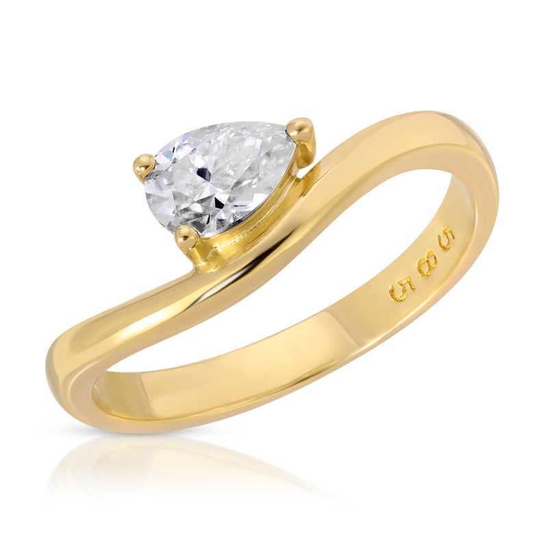 Pode incluir: Um anel de ouro com um diamante em forma de p&ecirc;ra engastado em uma banda torcida. O anel &eacute; marcado com "CT 0.05".