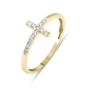 May include: A gold ring with a small, diamond-encrusted cross design. The cross is set on a thin band that is also encrusted with diamonds.