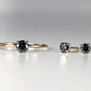 Puede incluir: Un conjunto de tres anillos de oro con piedras preciosas azules. El anillo de la izquierda es un anillo solitario con una piedra preciosa m&aacute;s grande. Los dos anillos de la derecha son m&aacute;s peque&ntilde;os y tienen piedras preciosas m&aacute;s peque&ntilde;as.