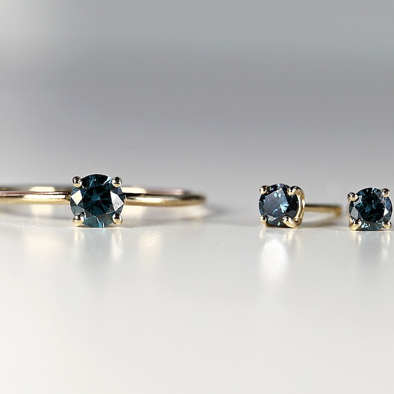 Puede incluir: Un conjunto de tres anillos de oro con piedras preciosas azules. El anillo de la izquierda es un anillo solitario con una piedra preciosa m&aacute;s grande. Los dos anillos de la derecha son m&aacute;s peque&ntilde;os y tienen piedras preciosas m&aacute;s peque&ntilde;as.