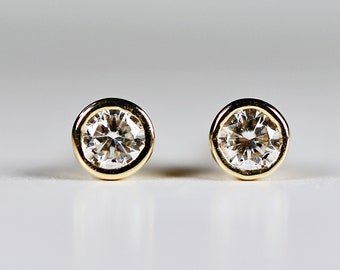 May include: A pair of gold stud earrings with round, clear gemstones.