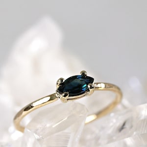 A gold ring with a marquise-shaped blue green sapphire gemstone.