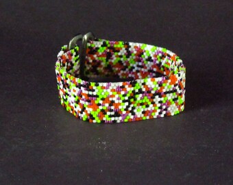 May include: A colourful beaded bracelet featuring a mix of white, black, orange, green, and purple beads. The bracelet is secured with a silver-coloured clasp.