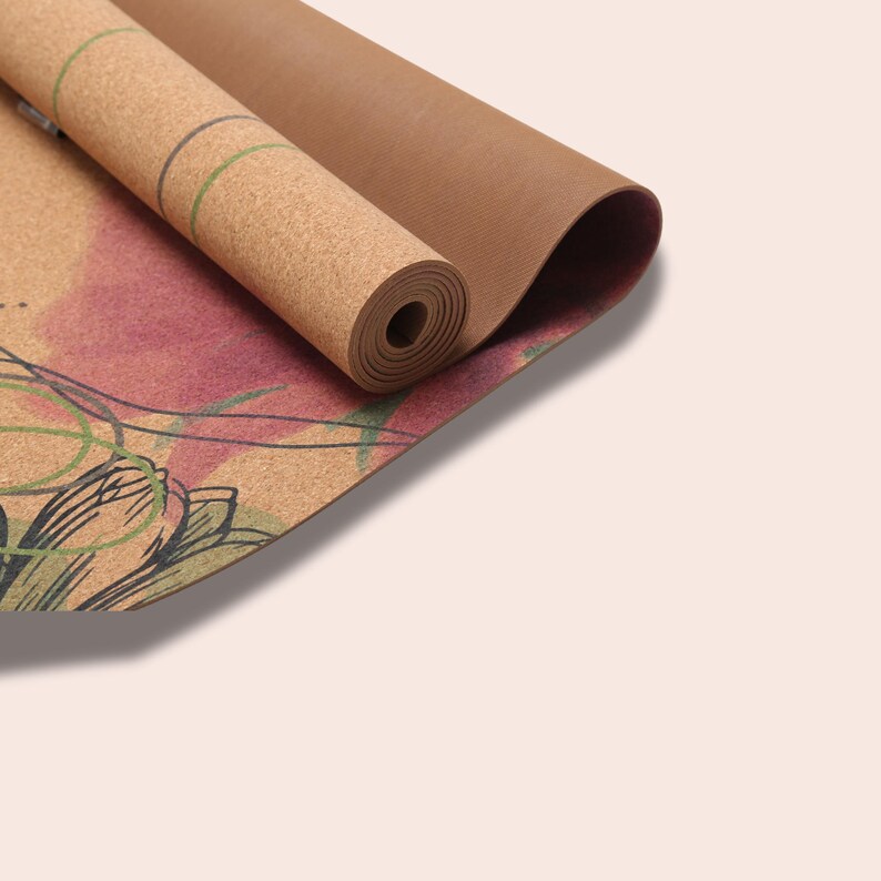 May include: A rolled up cork yoga mat with a floral design. The mat is brown with a light brown underside and has a green and pink floral pattern.