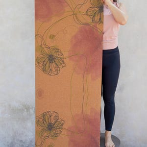 May include: A cork yoga mat with a floral design in shades of brown, green, and pink. The mat features a repeating pattern of stylised flowers and bees.