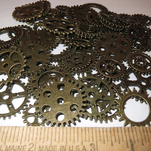 May include: A pile of antique gold-toned metal gears of various sizes. The gears are arranged in a random pattern and are all in focus.