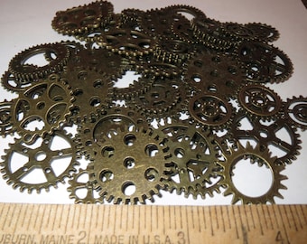 May include: A pile of antique gold-toned metal gears of various sizes. The gears are arranged in a random pattern and are all in focus.