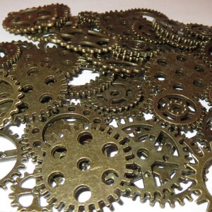 May include: A collection of antique gold-toned metal gears of various sizes. The gears are arranged in a random pattern, creating a visually interesting and intricate design.