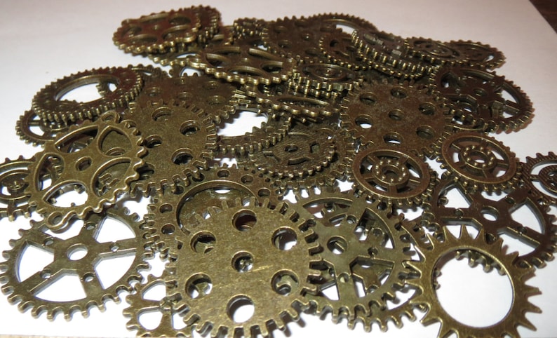 May include: A collection of antique gold-toned metal gears of various sizes. The gears are arranged in a random pattern, creating a visually interesting and intricate design.