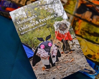 May include: A book cover with the title "Mothman's Oddities & Peculiars" and the subtitle "Bigfoot Fall Capsule Collection". The cover features a black moth-like creature with pink eyes and a red-clad humanoid figure with a long, furry beard.