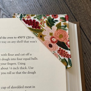 May include: A triangular bookmark with a floral pattern in shades of pink, red, and green. The bookmark is made of fabric and has a stitched edge. The text "Garden Party Rose" is visible at the top of the image.