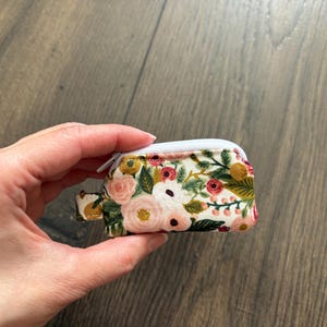 May include: A white ceramic mug with a black handle and the text "But First, Coffee" in a black, bold font. The mug is on a white surface.