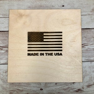 Puede incluir: Una placa de madera con una bandera estadounidense en blanco y negro y el texto "MADE IN THE USA".