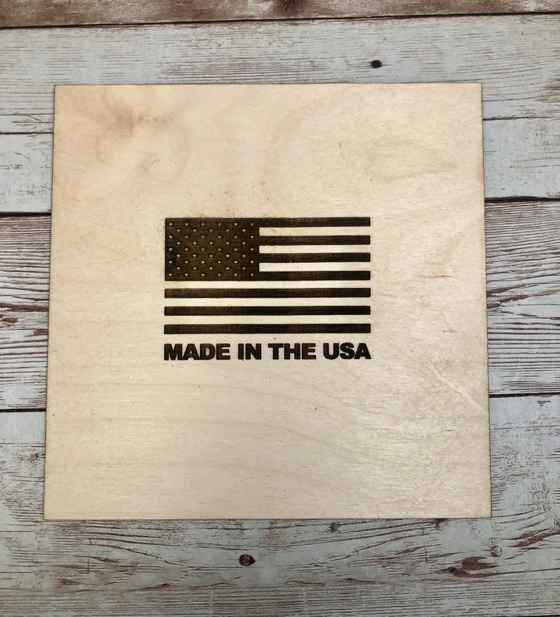 Puede incluir: Una placa de madera con una bandera estadounidense en blanco y negro y el texto "MADE IN THE USA".