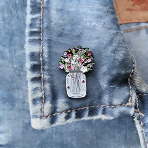 Broche de lapela com buquê floral em pote de vidro com desenho de flores silvestres