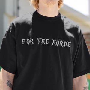 Könnte beinhalten: Ein schwarzes T-Shirt mit dem Text "FOR THE HORDE" in einer stilisierten Schrift.