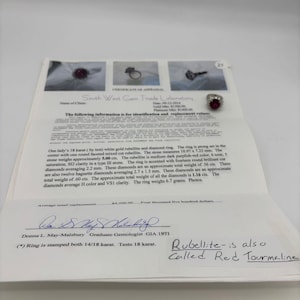 May include: A certificate from South West Gem Trade Laboratory details a white gold ring with a rubellite and diamonds. The ring features a mixed-cut rubellite, approximately 10.97 x 7.23 mm, and fourteen round brilliant-cut diamonds. The ring weighs 6.7 grams.