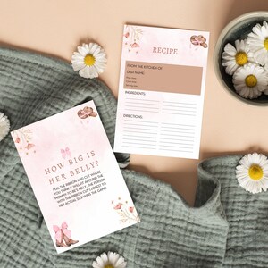 Peut inclure: Une carte de jeu de baby shower rose et marron avec le texte "How big is her belly?" et des instructions pour tirer un ruban et couper o&ugrave; vous pensez qu'il ira autour du ventre de la future maman. La personne dont la coupe de ruban est la plus proche de sa taille r&eacute;elle gagne le jeu.