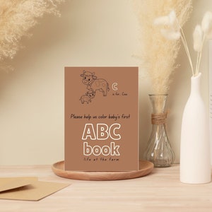 Op de afbeelding: Een bruine kaart met een zwart-witte illustratie van een koe en een kalf. De tekst op de kaart luidt "C is voor Cow. Help ons om baby's eerste ABC-boek te kleuren het leven op de boerderij."