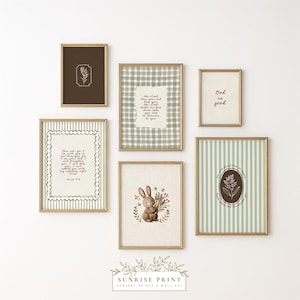 May include: A collection of framed wall art with gold frames. The art includes botanical illustrations, a bunny holding flowers, and inspirational quotes. The color palette is soft, with shades of brown, green, and white. The art is arranged on a white wall.