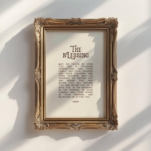 May include: Ornate gold-colored framed print with the text "The Blessing" in elegant script. The print features a prayer with the word "Amen" at the bottom. The frame has detailed scrollwork.