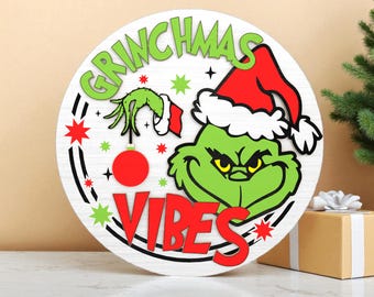 グリンチがここにいるクリスマスドアサインSVG - 雪の結晶とサンタ帽子