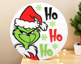 グリンチがここにいるクリスマスドアサインSVG - 雪の結晶とサンタ帽子