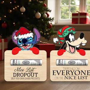 Puede incluir: Dos letreros de madera con temática navideña con personajes de Disney. Uno muestra a Stitch con un gorro de Papá Noel y el texto "Nice List Dropout". El otro muestra a Goofy con un gorro de elfo y el texto "Everyone on the Nice List". Cada letrero contiene un billete enrollado.