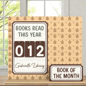 May include: Wooden book counter with the text "BOOKS READ THIS YEAR" and the number "012" displayed. The counter also includes the text "Gabrielle Library" and "BOOK OF THE MONTH". The background has a light brown floral pattern.