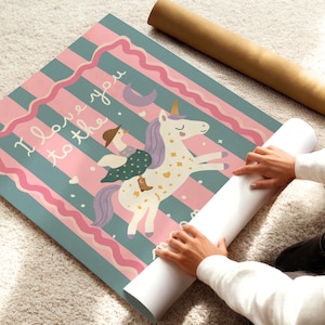 May include: A rolled-up poster featuring a whimsical illustration of a unicorn with a rider, set against a striped background of teal and pink. The text "I love you to the..." is visible. A brown cardboard tube is also present.