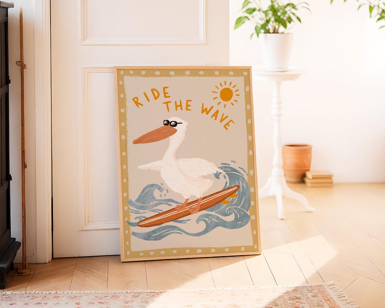 K&ouml;nnte beinhalten: Ein beige-brauner gerahmter Druck mit einem wei&szlig;en Pelikan, der eine Sonnenbrille tr&auml;gt und auf einer blauen Welle surft. Der Text "Ride the Wave" ist in gelben und orangefarbenen Buchstaben geschrieben.