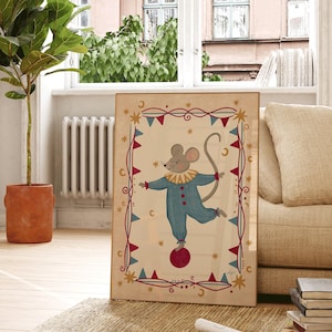 May include: A framed rectangular wall art print featuring a central illustration of a grey mouse wearing a blue clown suit with a yellow ruffled collar, balancing on a red ball, surrounded by a decorative border of red and blue triangular flags.