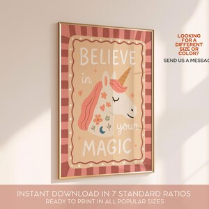 May include: A framed print with a gold border features a unicorn illustration and the words "BELIEVE in your MAGIC." The unicorn has a pink mane and a golden horn. The background is a light tan color with a pink and brown border. The text "LOOKING FOR A DIFFERENT SIZE OR COLOR? SEND US A MESSAGE!" is also visible.