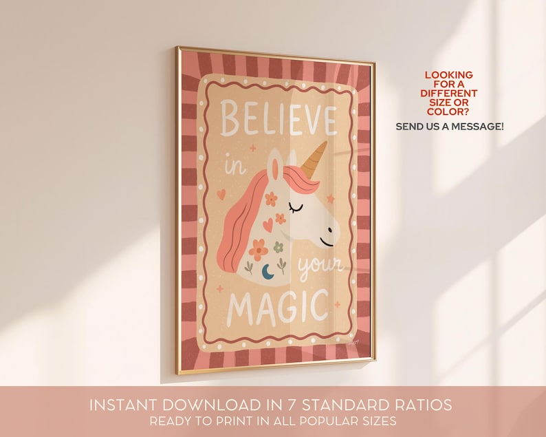 May include: A framed print with a gold border features a unicorn illustration and the words "BELIEVE in your MAGIC." The unicorn has a pink mane and a golden horn. The background is a light tan color with a pink and brown border. The text "LOOKING FOR A DIFFERENT SIZE OR COLOR? SEND US A MESSAGE!" is also visible.