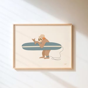 May include: A framed print featuring a cartoon sloth wearing a hat and headphones, holding a blue surfboard. The sloth is giving a hand gesture. The artwork has a light beige background and a wooden frame.