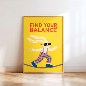 Puede incluir: Un póster enmarcado con fondo amarillo presenta un conejo de dibujos animados con gafas de sol y pantalones a cuadros, equilibrándose en una cuerda floja. Las palabras "FIND YOUR BALANCE" están en rojo en la parte superior. El póster está en un marco de madera.