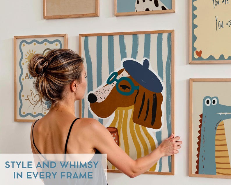 May include: A collection of framed illustrations featuring whimsical animal characters. The illustrations are in a modern style with bold colors and simple lines. The frames are all wooden and have a natural finish. The illustrations include a dog wearing a beret and glasses, a crocodile with large eyes, and a bird with a sun behind it.