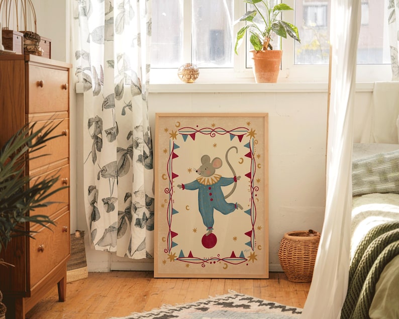 May include: A framed rectangular wall art print featuring a central illustration of a mouse wearing a blue clown suit with a yellow ruffled collar, balancing on a red ball. The border includes red and blue bunting, gold stars, and crescent moons.