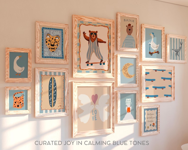 May include: A gallery wall of framed prints with a blue and white color scheme. The prints feature various designs, including animals, words, and abstract patterns. The frames are all made of light wood and have a rustic look. The text on the prints includes "It's Cool to Be Kind", "Bonjour", "Own Your Sparkle", and "Love".