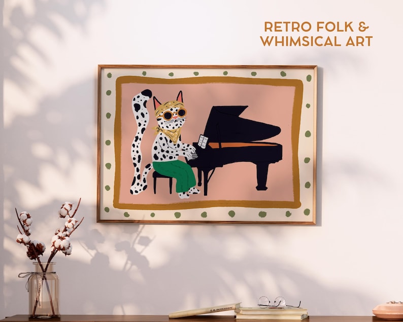 May include: A framed art print featuring a whimsical illustration of a spotted cat playing a black grand piano. The cat wears sunglasses and green pants. The print has a pink background and the text "RETRO FOLK & WHIMSICAL ART".